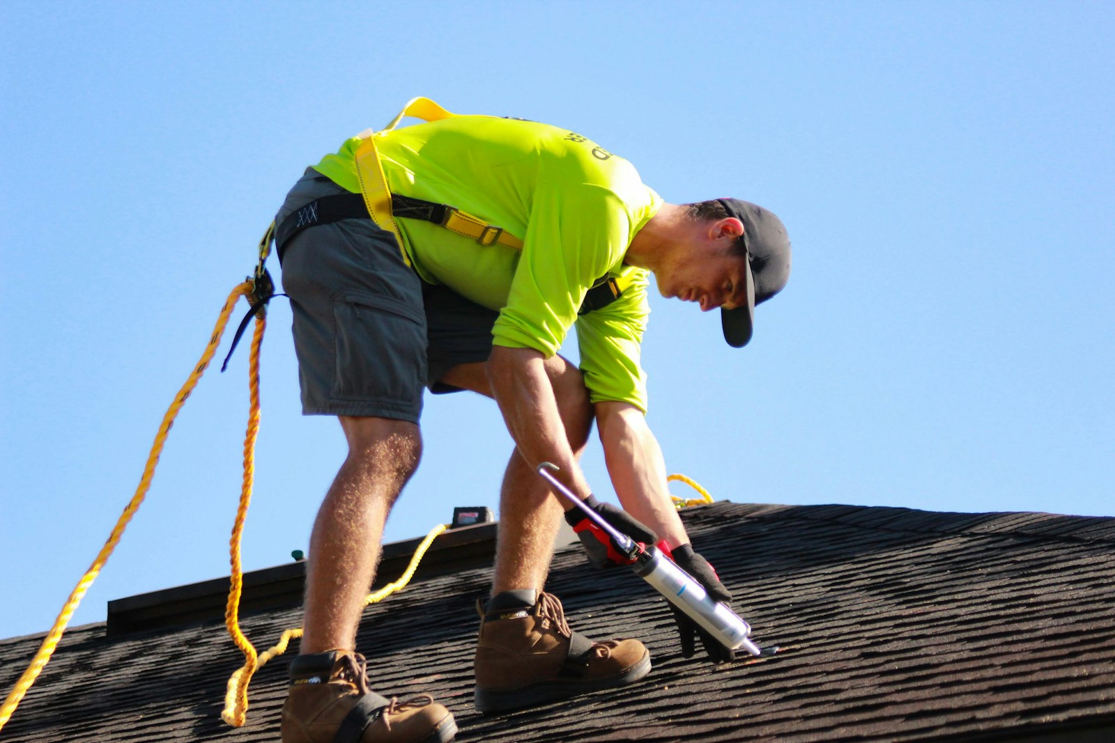 Roofer in a harness sealing shingles on a residential roof
